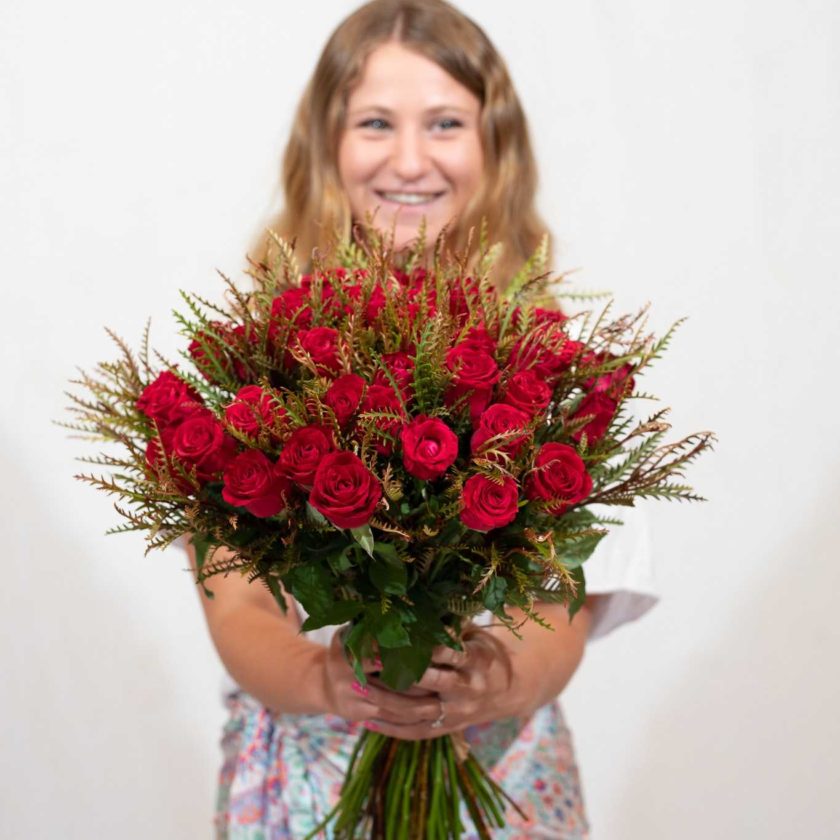 אישה מציגה זר ורדים אדומים